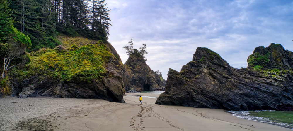 A person walk on the beach between rock formations