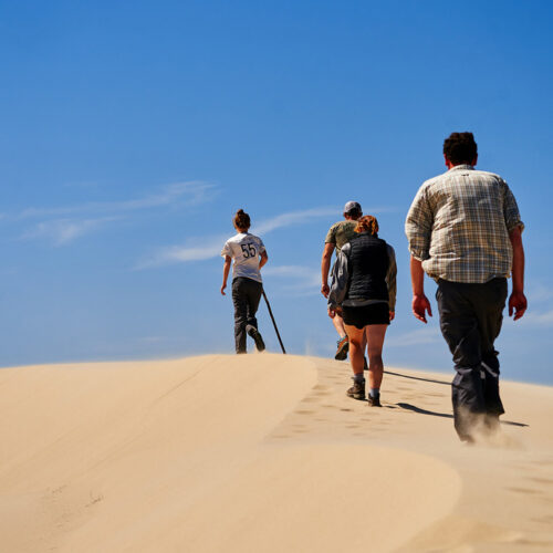 sand dunes people hiking daytime Coos Bay sq